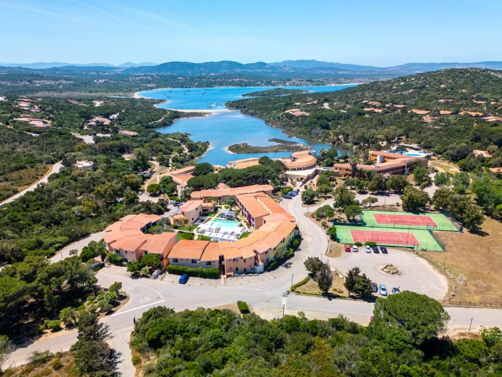 Vista aerea del resort con campi da tennis e la laguna che si apre verso il mare