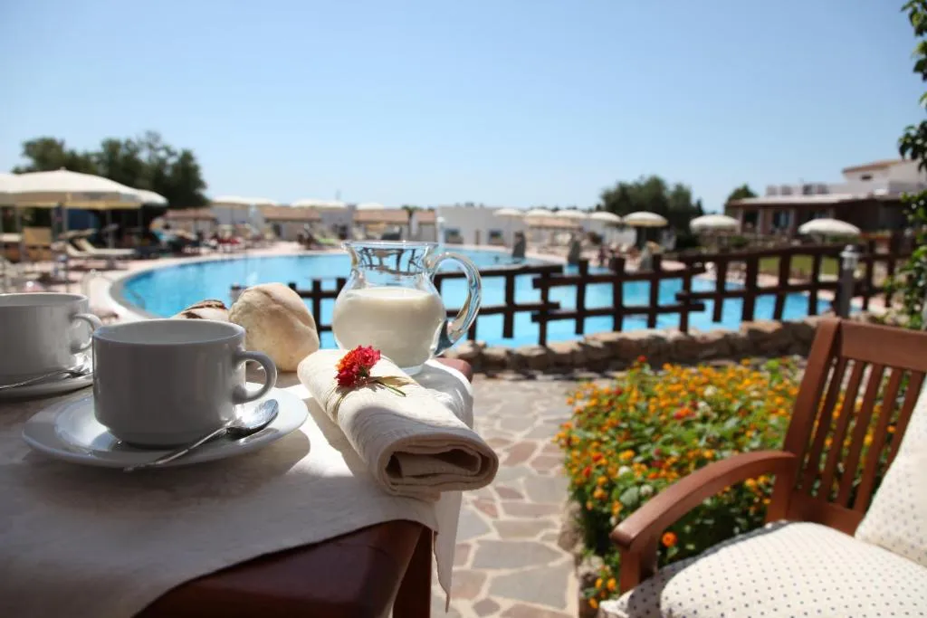 Colazione servita su tavolo con tazze e brocca di latte affacciata sulla piscina