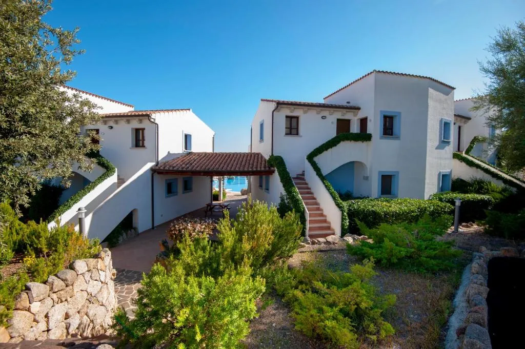 Residenze bianche a due piani con scale esterne e giardino mediterraneo, scorcio sul mare