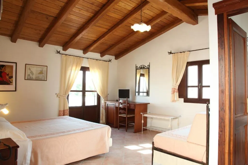Camera luminosa con soffitto in legno a travi, letto matrimoniale, scrivania e finestre