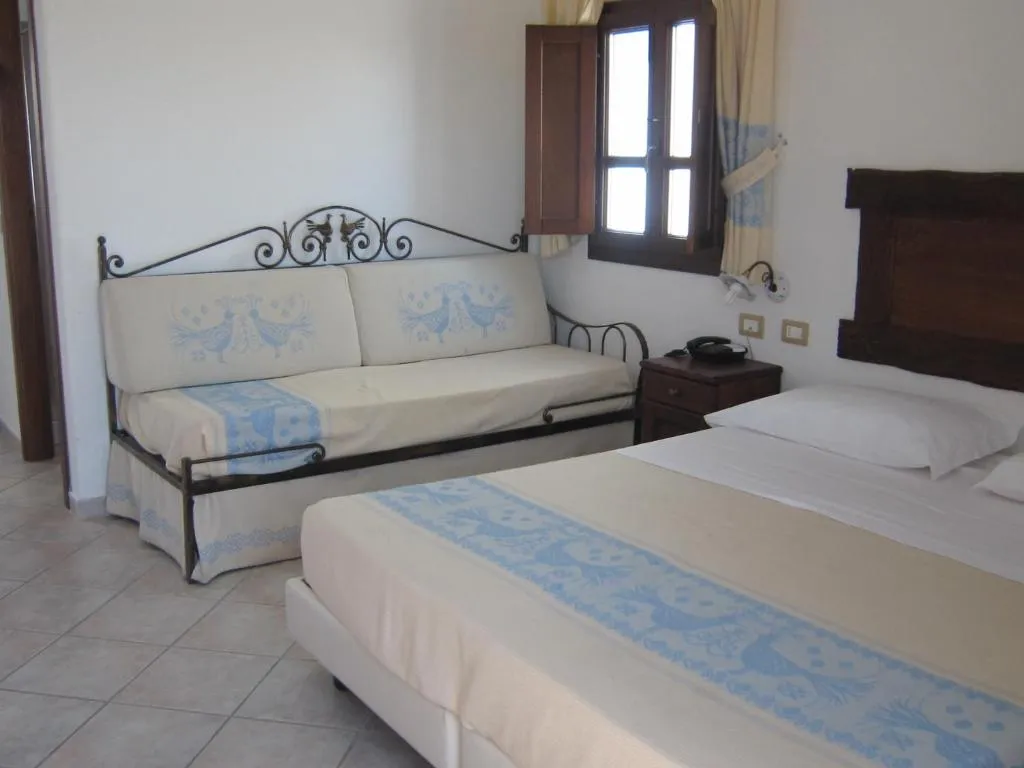 Camera da letto con letto matrimoniale, divano in ferro battuto e tessuti sardi azzurri