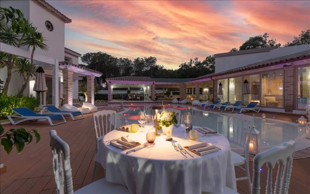 Tavolo apparecchiato per cena romantica a bordo piscina al tramonto
