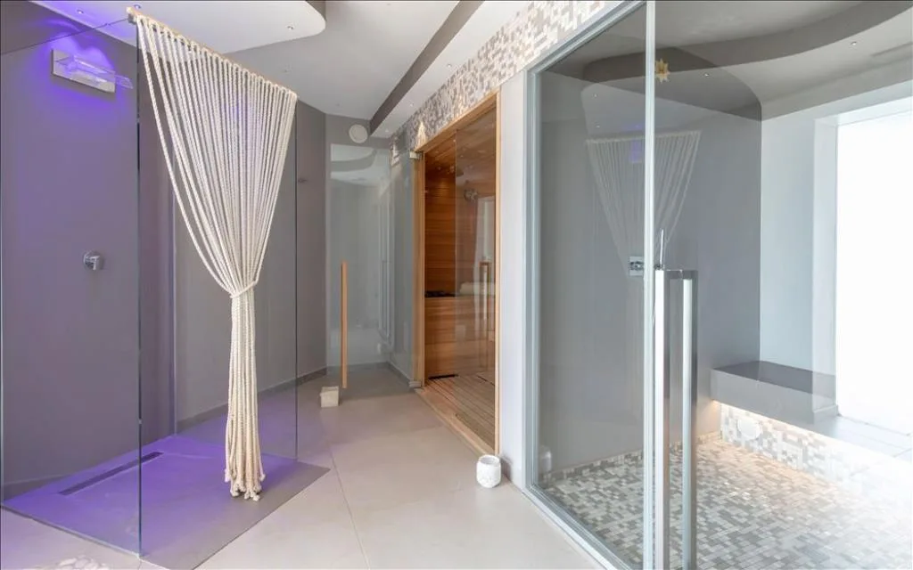 Area benessere con docce emozionali in vetro e sauna in legno