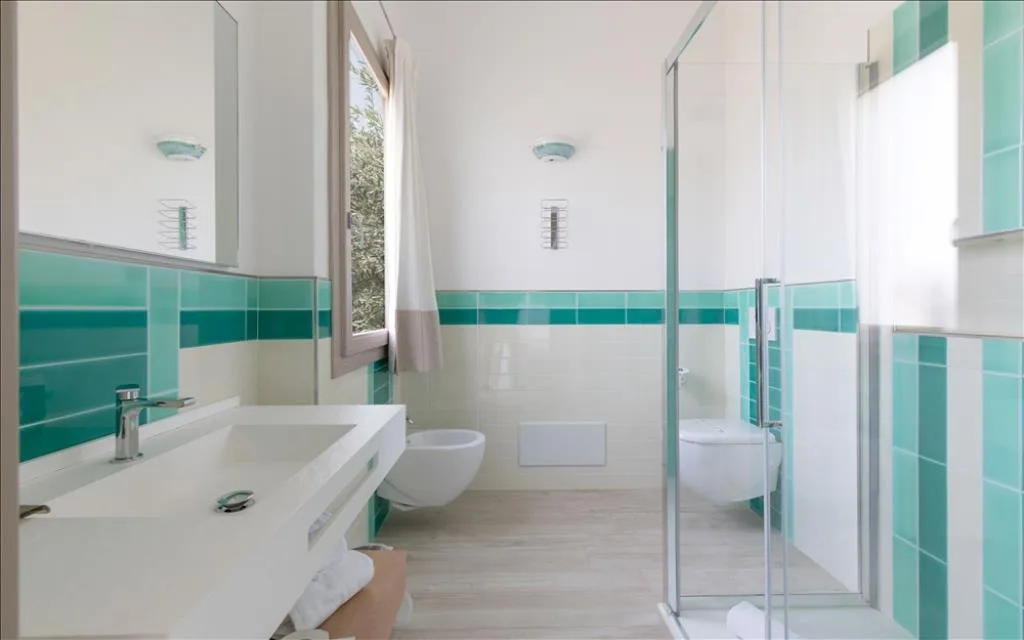 Bagno moderno con piastrelle verdi, doppio lavabo e doccia in vetro