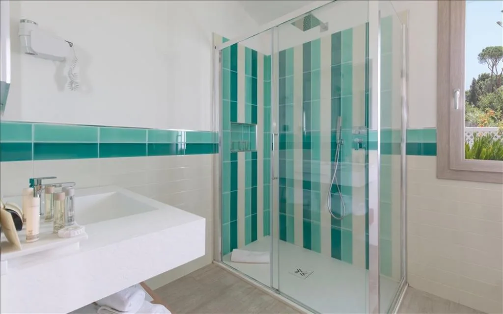 Bagno luminoso con piastrelle a righe verdi e doccia con box in vetro