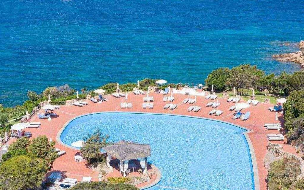 Piscina a sfioro affacciata sul mare con lettini e ombrelloni