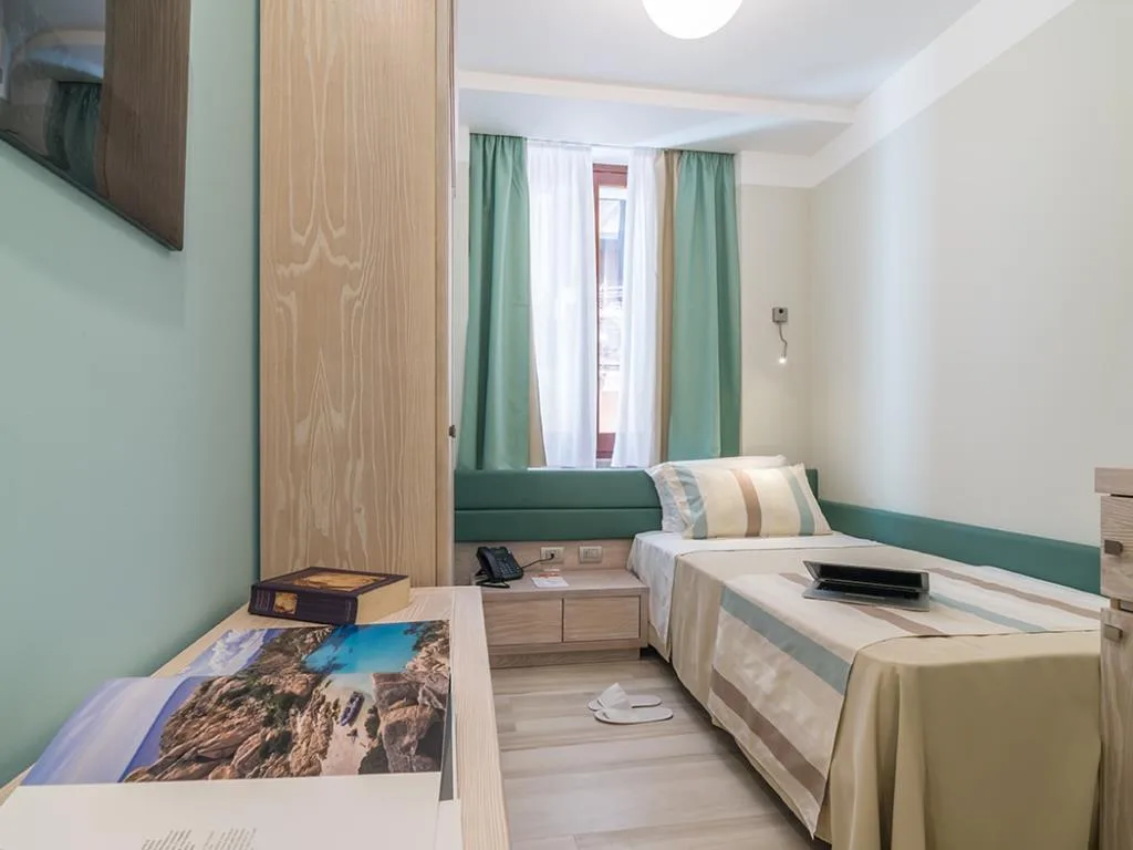 Camera singola con letto, tende verdi, comodino e finestra luminosa