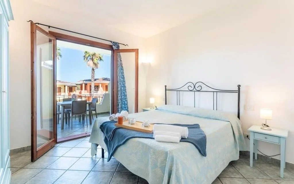 Camera matrimoniale con testiera in ferro battuto e accesso alla terrazza con vista palme