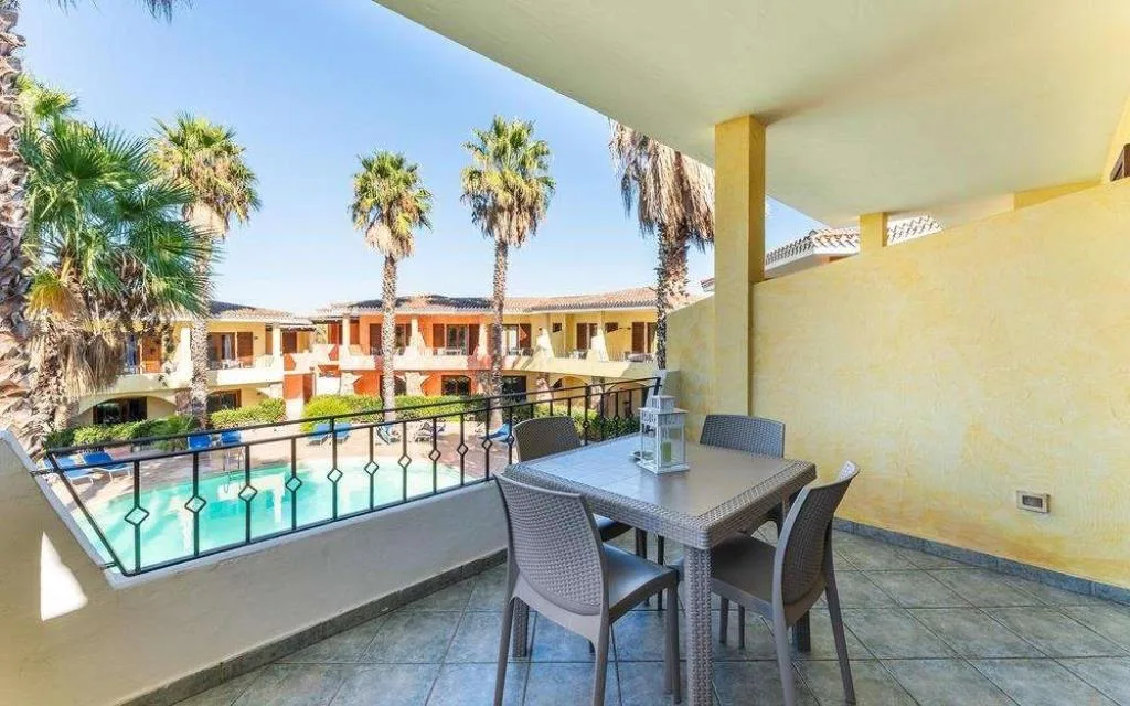 Terrazza con tavolo e sedie affacciata sulla piscina e sul giardino con palme