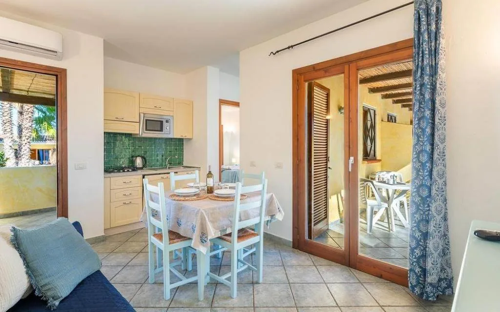 Soggiorno con angolo cottura, tavolo da pranzo e accesso alla veranda