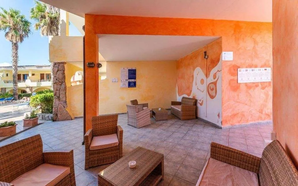 Area lounge esterna con poltrone in rattan e pareti color arancio
