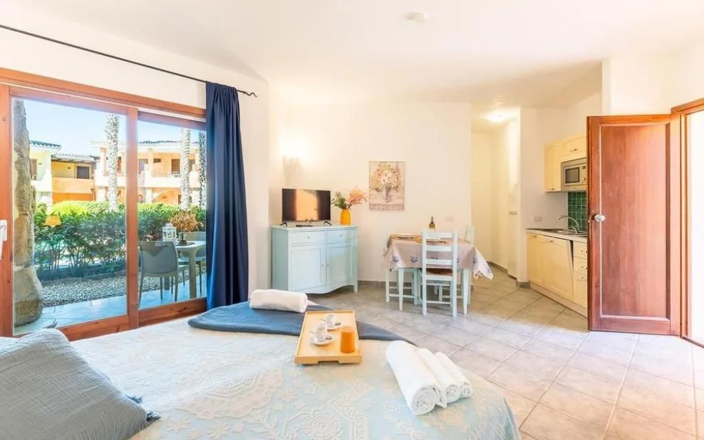 Appartamento con letto, angolo cottura e uscita sul patio con giardino