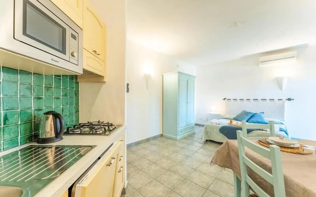 Angolo cottura con microonde, fornelli e camera da letto sullo sfondo