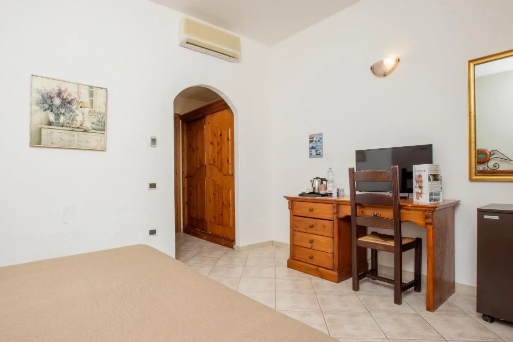 Camera da letto con scrivania in legno, TV, aria condizionata e ingresso ad arco